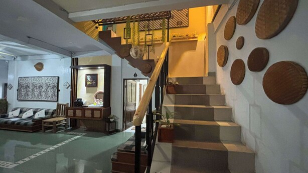 Un escalier doté d’une rampe en bois et d’un mur orné de paniers tressés de forme circulaire.