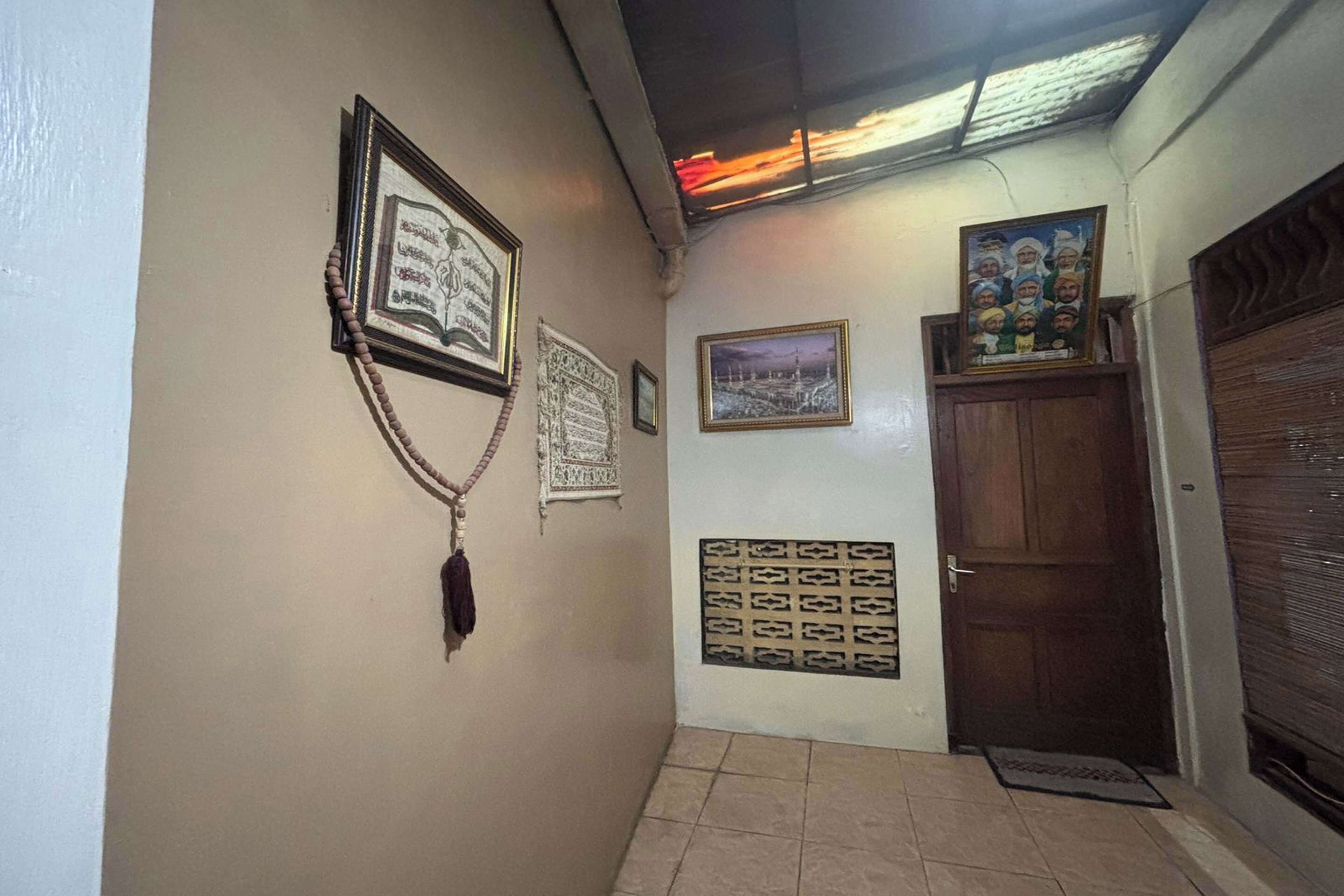 Um corredor com textos religiosos emoldurados, uma porta e uma parede estampada.