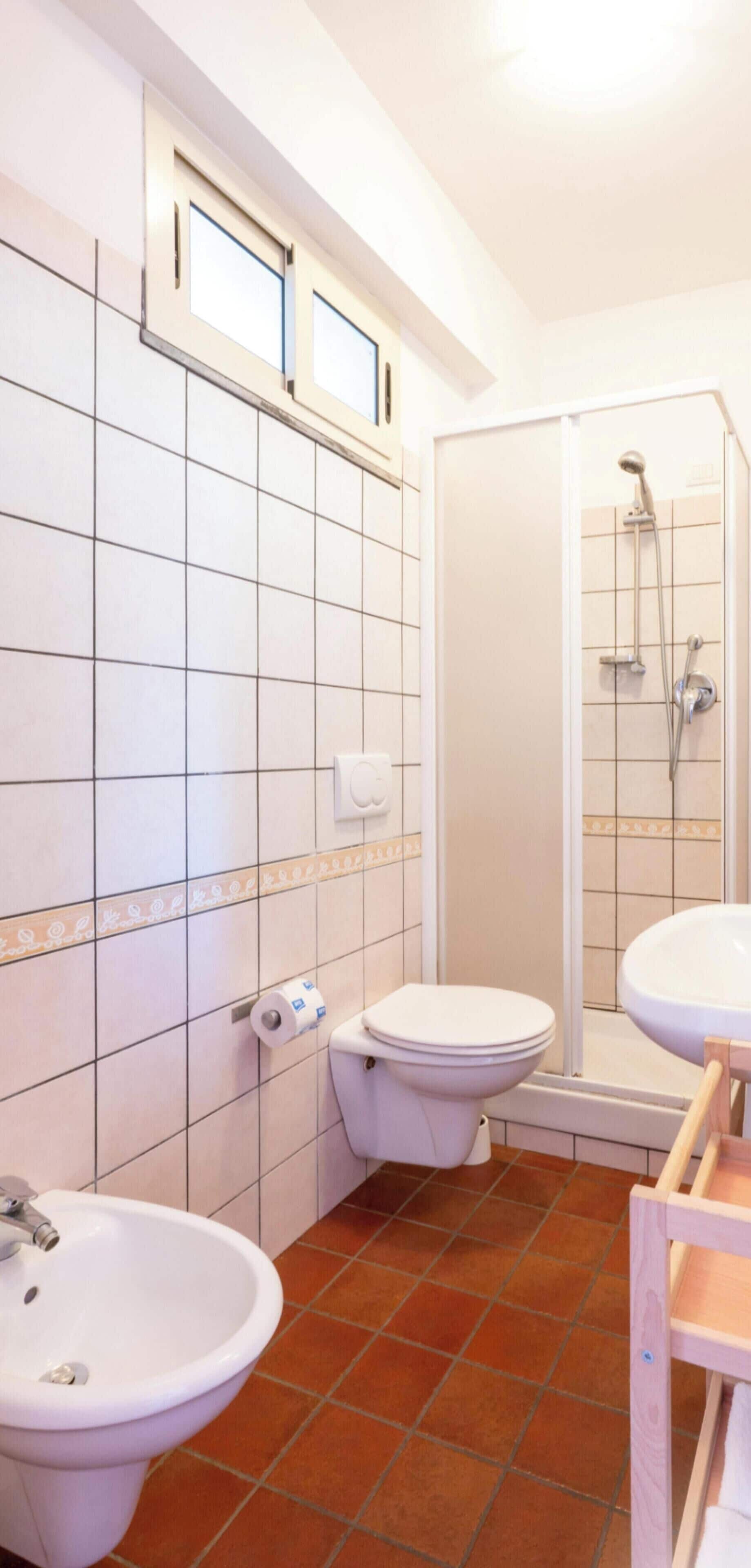 A bathroom with a toilet, bidet, and shower.