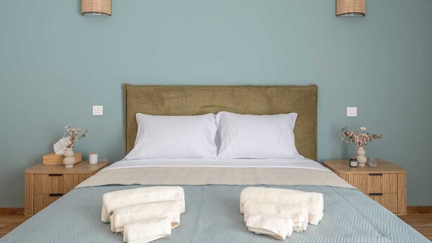 Ein Schlafzimmer mit einem Bett, zwei Nachttischen, einem Kopfteil und zwei Wandlampen.