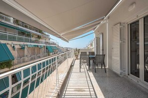 A balcony with a table and chairs, a potted plant, and a view of the sea. - Penthouse Acropolis View Sunset Balcony (Athina)