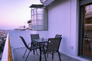 Ein Balkon mit Tisch und Stühlen, einer Glasveranda und Blick auf die Stadt.
