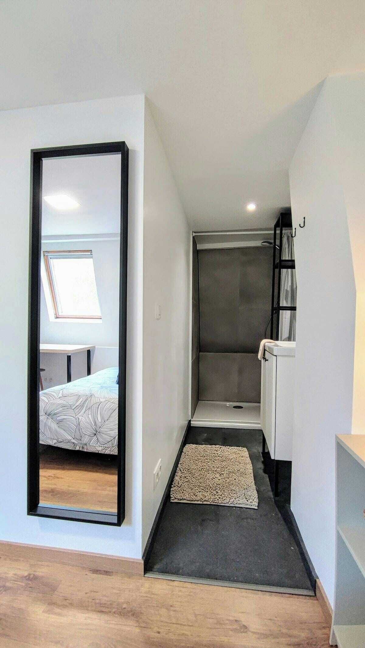Un corridoio stretto con un letto, un termosifone e un tavolino.