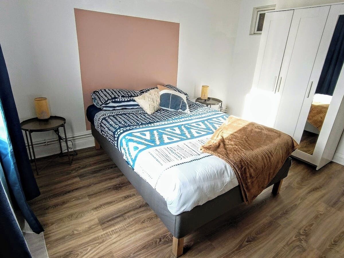 A bedroom with a bed, bedside tables, a wardrobe, and a small table with a lamp.