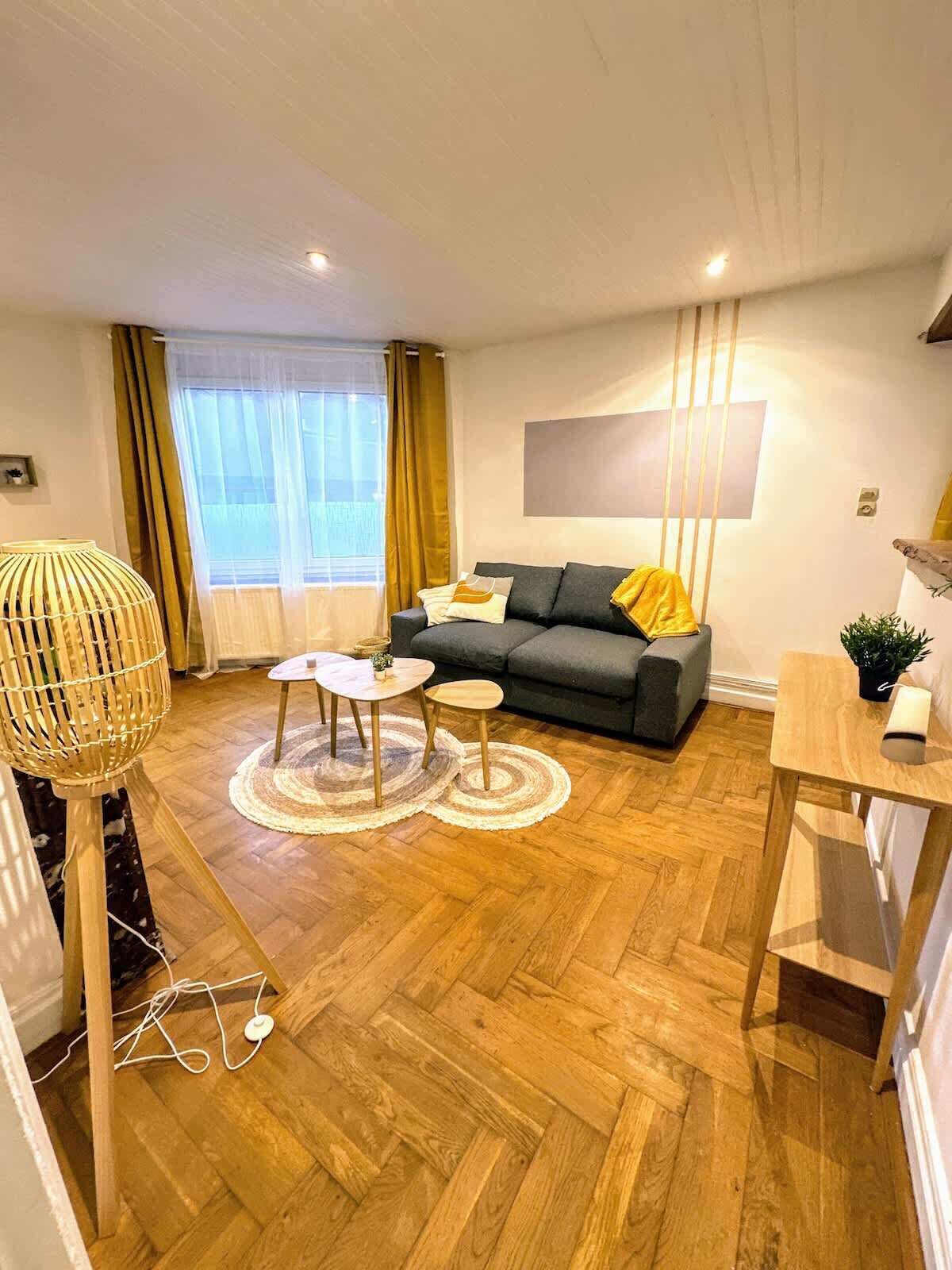 Ein modernes Wohnzimmer mit einem grauen Sofa, zwei runden Tischen und Holzdielen.