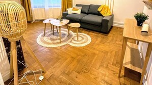Ein modernes Wohnzimmer mit einem grauen Sofa, zwei runden Tischen und Holzdielen.