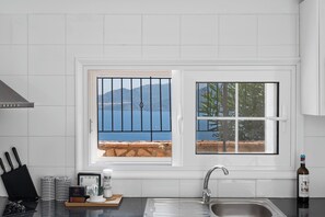 A kitchen with a view of the sea, a sink, and a window with metal bars. - Villa Fortuna, Villa (Lefkada)