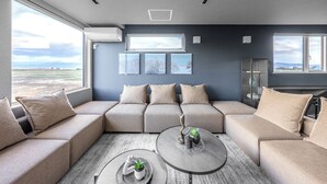 Una sala de estar moderna con un sofá modular, una mesa de centro y grandes ventanales con vistas al exterior.