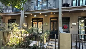 Un immeuble de deux étages doté d’un balcon, d’une entrée fermée par un portail et d’une enseigne indiquant l’adresse 123A.