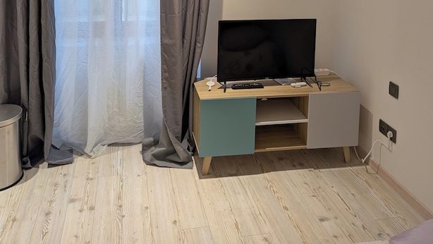 A modern room with a wooden desk, a flat-screen TV, and a grey curtain. - Chez steph (Le Puy-en-Velay)