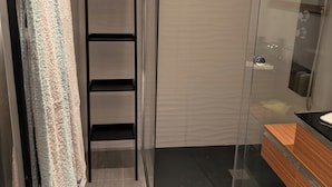 A modern bathroom with a glass shower enclosure, a wooden vanity, and a towel rack with a striped towel. - Chez steph (Le Puy-en-Velay)