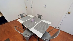 Una mesa rectangular con tapa blanca y centro con estampado de cuadrícula gris, rodeada por cuatro sillas grises.