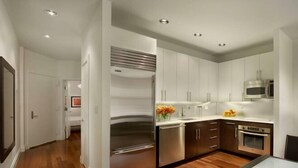 A modern kitchen with stainless steel appliances, wooden flooring, and white cabinetry. - XL Prime Tribeca Furnished Loft (New York)