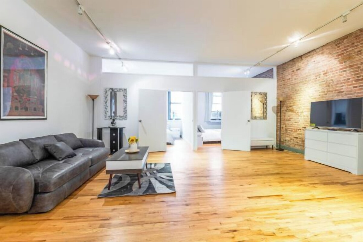 Een moderne woonkamer met een leren bank, een salontafel en een flatscreen televisie tegen een bakstenen muur.