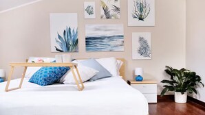Une chambre à coucher avec un lit, des tables de chevet et des œuvres d’art murales.
