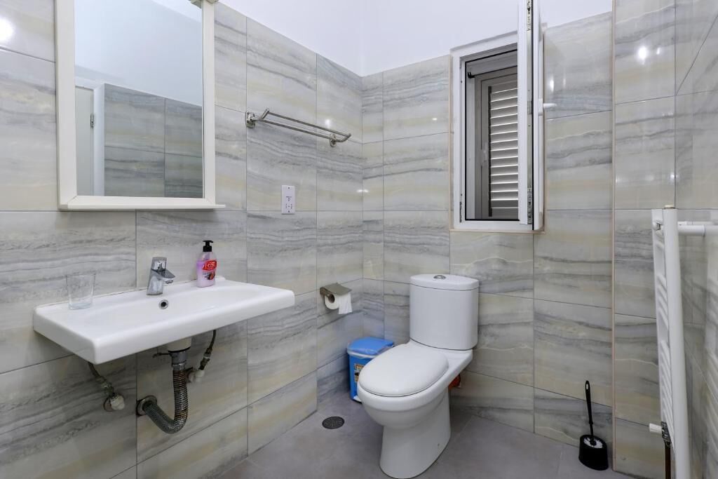 Un baño con lavamanos blanco, espejo, inodoro y ducha.