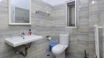 Un baño con lavamanos blanco, espejo, inodoro y ducha.