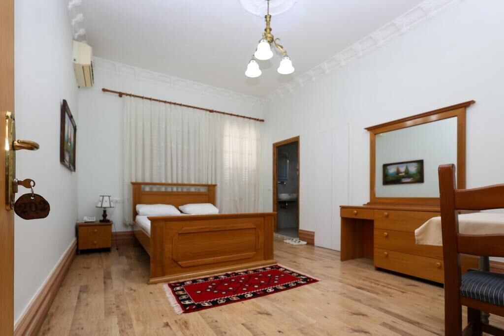 Un dormitorio con una cama de madera, una mesita de noche, un escritorio y una silla.