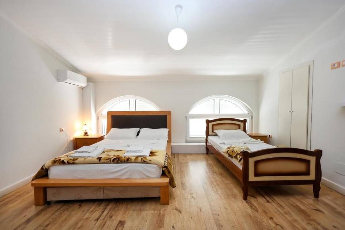 A bedroom with two wooden beds, a ceiling light, and a window with a white frame.