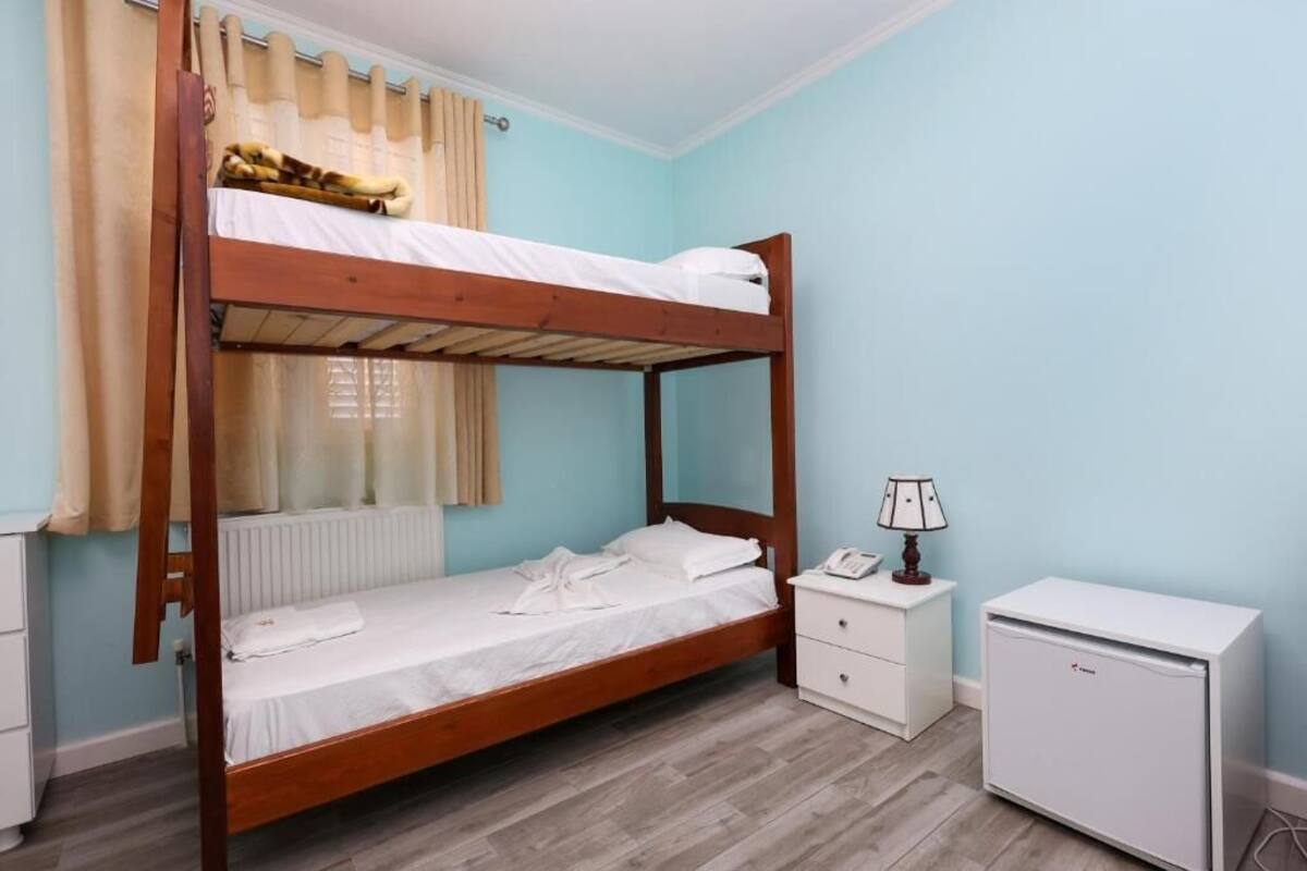 A bunk bed room with a white cabinet and a small white refrigerator.