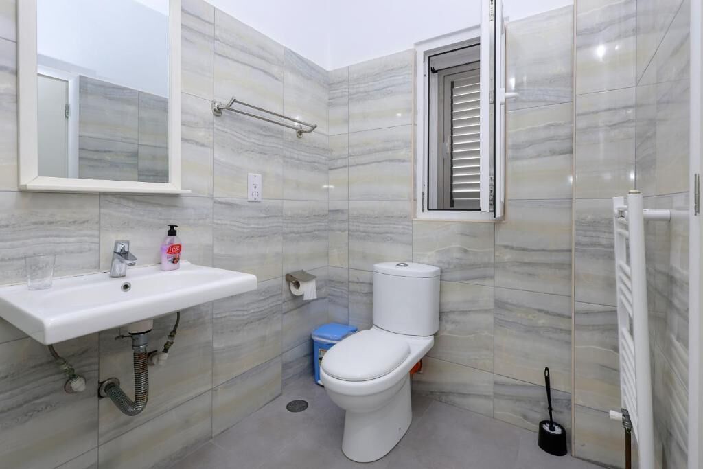 Un baño pequeño con un lavamanos blanco, un inodoro y una ventana con persianas.
