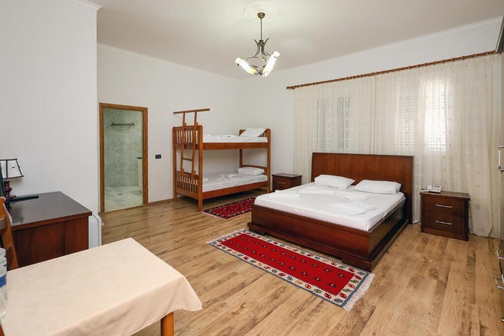 Un dormitorio con una cama litera de madera, una cama individual, un escritorio y una silla.