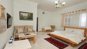 A room with a bed, a sofa, a small table, and a chair.
