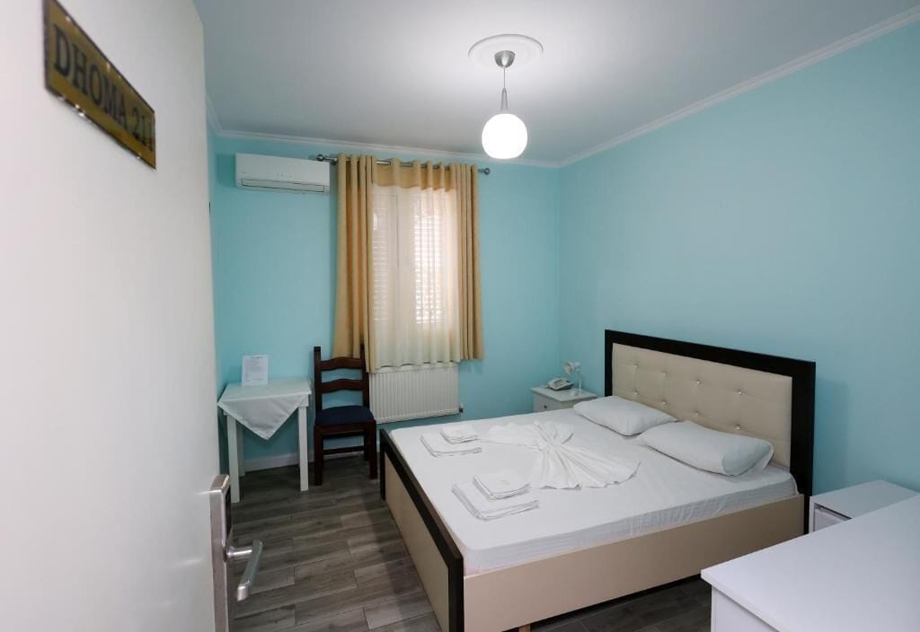Un dormitorio con cama, escritorio, silla y radiador.