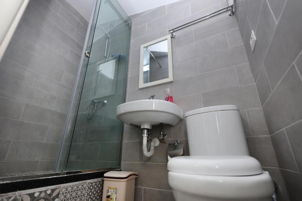 Un baño con cabina de ducha de vidrio, un lavamanos blanco y un inodoro.