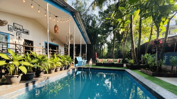A swimming pool with a covered area, potted plants, and a view of trees. - The Plix Villa (Vagator)