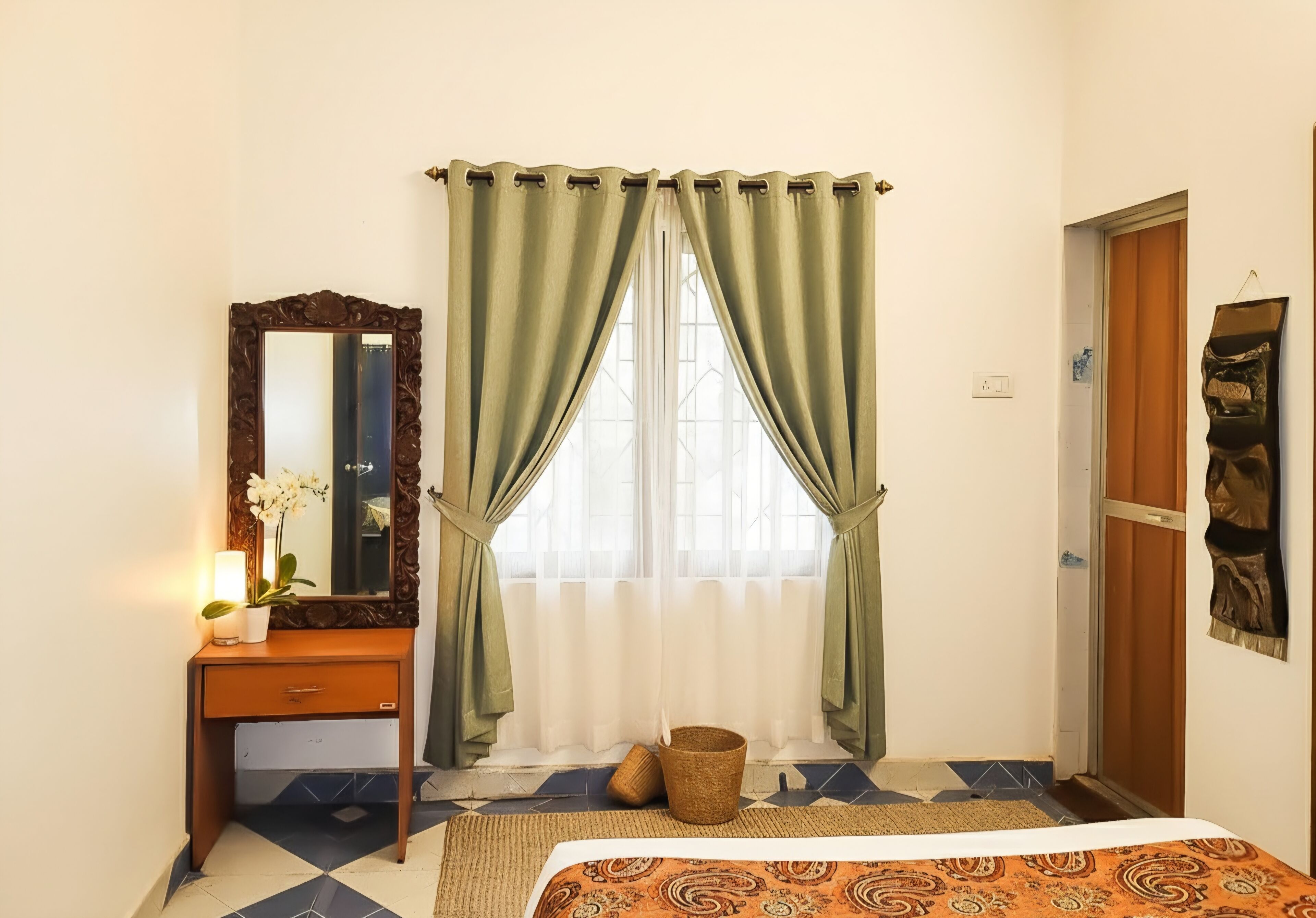 Une chambre à coucher avec un lit, une commode en bois, un miroir et une fenêtre avec des rideaux.