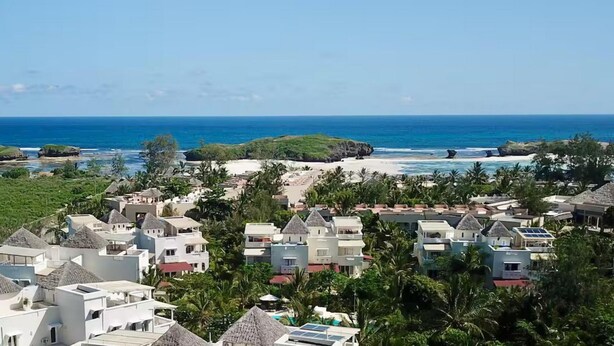 A coastal resort with thatched-roof buildings, a sandy beach, and a view of the ocean. - Tranquil Villa Apartment in Papa Remo Village-2326 (Watamu)