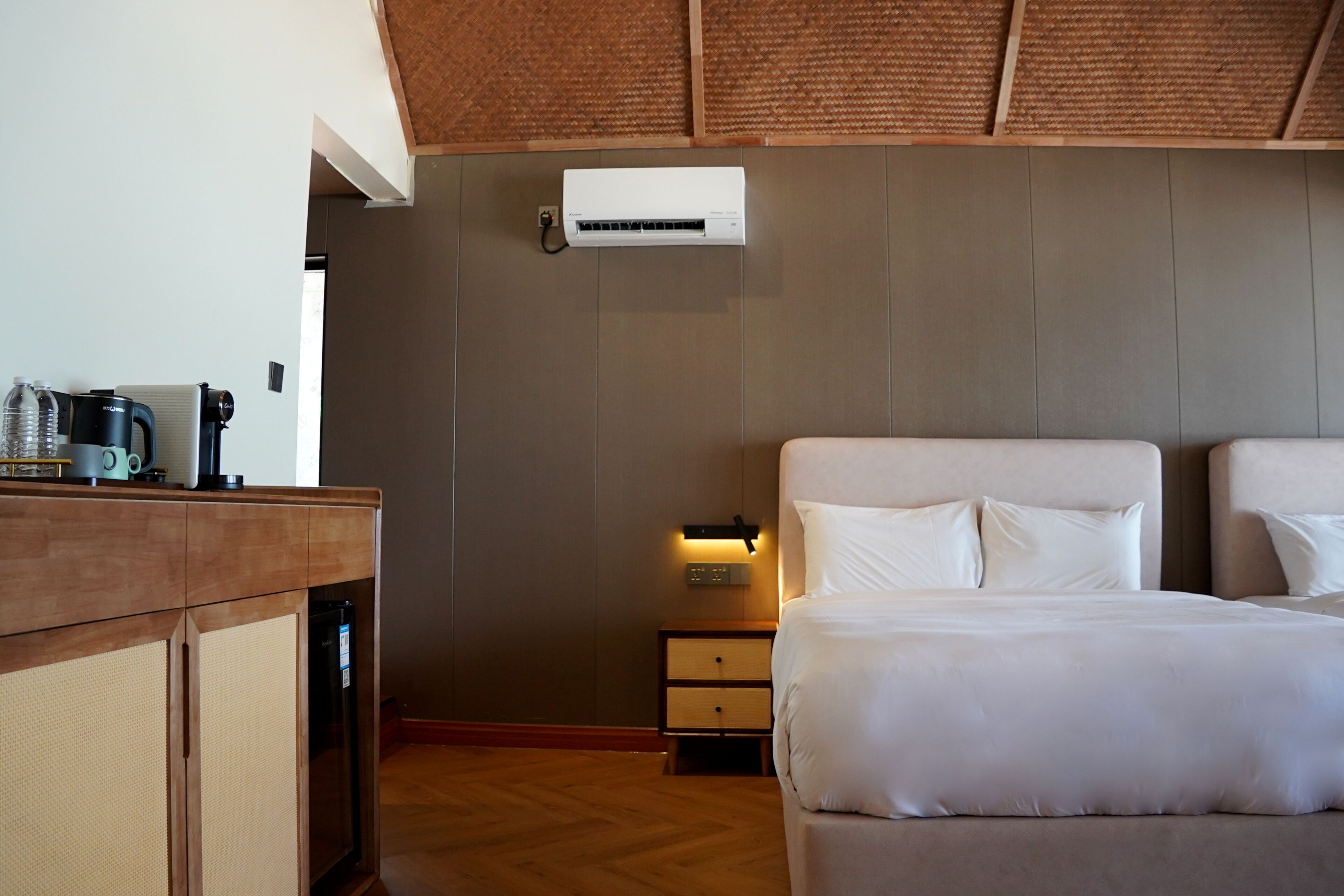 A hotel room with a bed, bedside table, and a small nightstand.