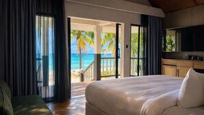 Ein Schlafzimmer mit einem großen Bett, einem Fernseher und Blick auf den Strand.