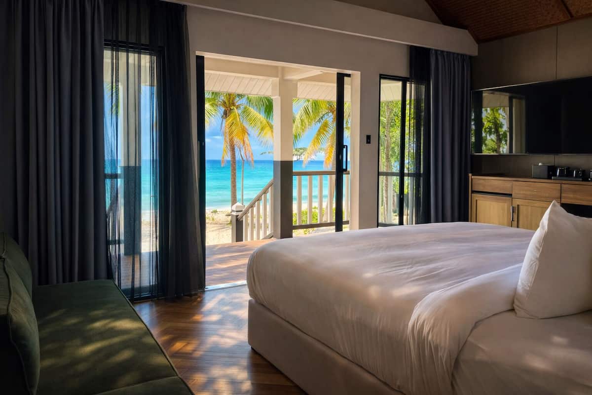 A bedroom with a large bed, a TV, and a view of the beach.