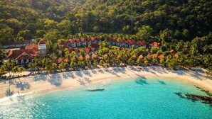 Ein Resort mit Strandvillen, einem Sandstrand und einem klaren türkisblauen Meer.