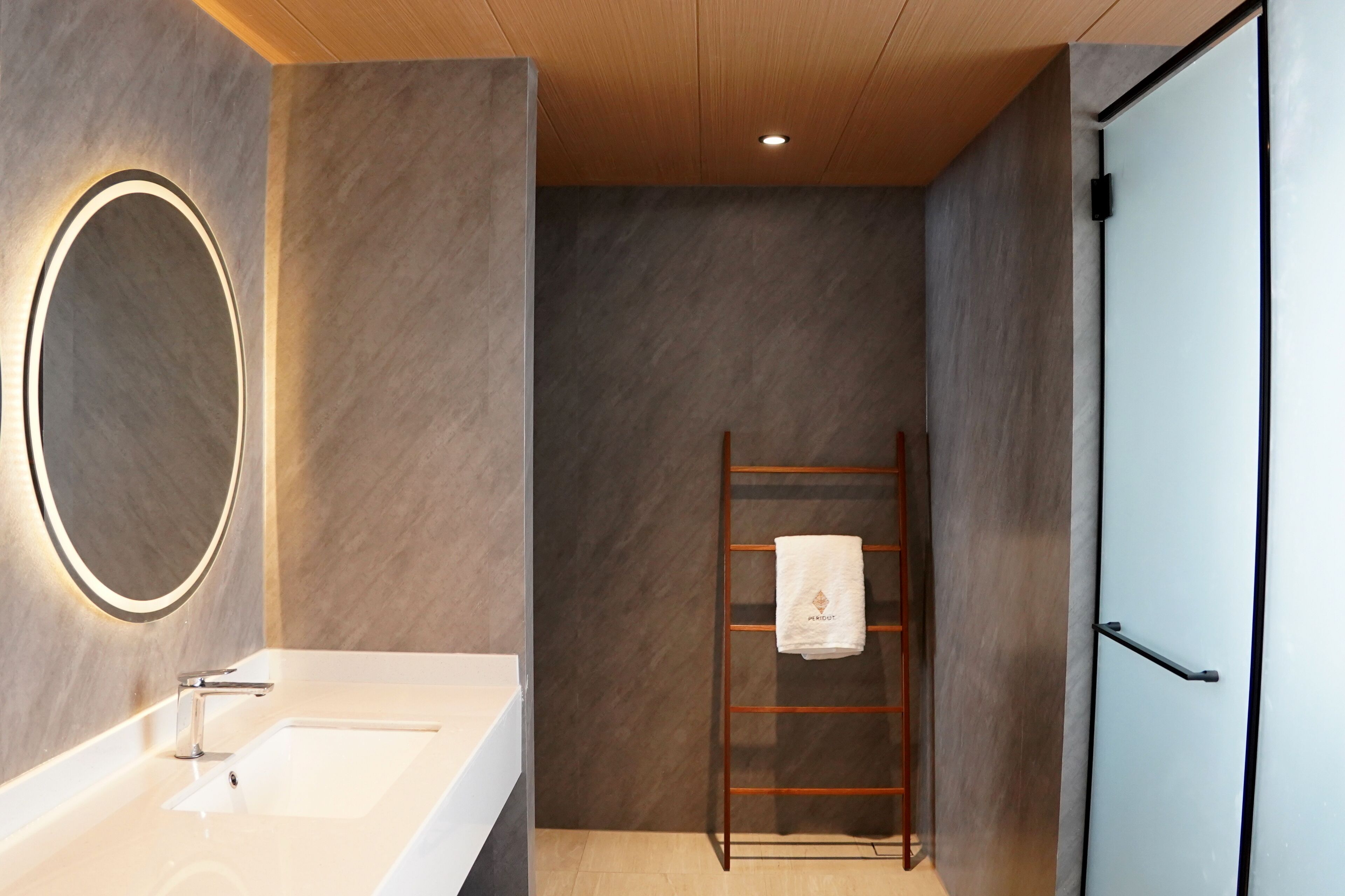 A modern bathroom with a large mirror, a sink, and a towel rack.