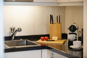 A modern kitchen with a sink, a coffee machine, and a cutting board with tomatoes. - North Sea - Modern and central 2-room apartment with balcony, WLAN. Pets (Sylt)