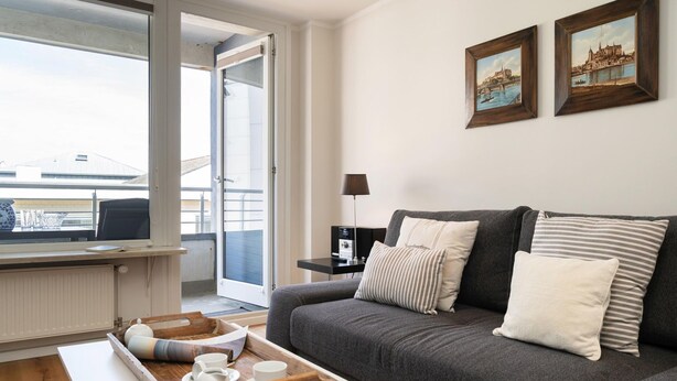 A modern living room with a grey sofa, a coffee table with a tray, and two framed pictures on the wall. - North Sea - Modern and central 2-room apartment with balcony, WLAN. Pets (Sylt)