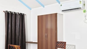 Une pièce avec une table et des chaises en bois, une armoire et un appareil de climatisation.