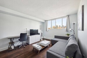 Ein modernes Wohnzimmer mit einer Couch, einem Couchtisch, einem Fernseher und einem Schreibtisch.