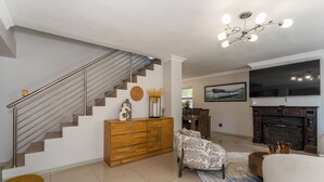 Ein modernes Wohnzimmer mit Treppe, Kamin und Flachbildfernseher.