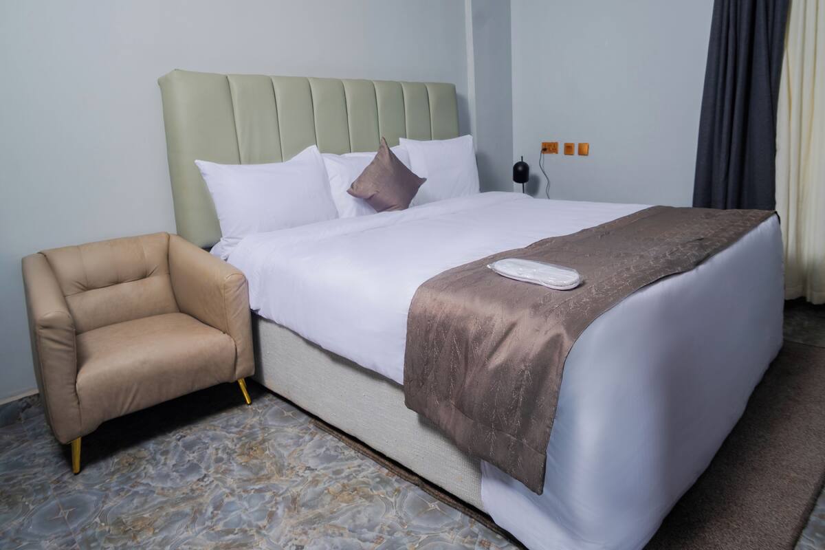 A hotel room with a bed, a chair, and a nightstand.