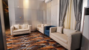 A modern hotel room with two sofas, a patterned floor, and an air conditioning unit on the wall. - Asato Hotel (Asaba)