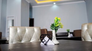 A dining area with a table set for two, a vase with yellow flowers, and a decorative heart-shaped object. - Asato Hotel (Asaba)