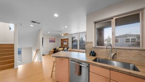 A modern kitchen with a large island, a built-in dishwasher, and a window overlooking a residential area. - Mission Bay Beach House/Roof-Top Deck/Parking (San Diego)
