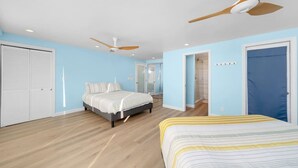 Un dormitorio con cama, armario, ventilador de techo y puerta al baño.