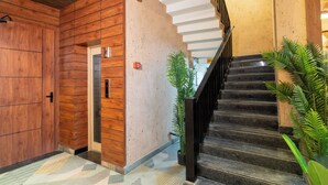 A staircase with a wooden wall and a metal railing, leading to an upper floor. - Hotel Sky Inn (Lucknow)