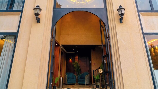 A building with a large arched entrance, two side windows, and a balcony with railings. - Hotel Sky Inn (Lucknow)