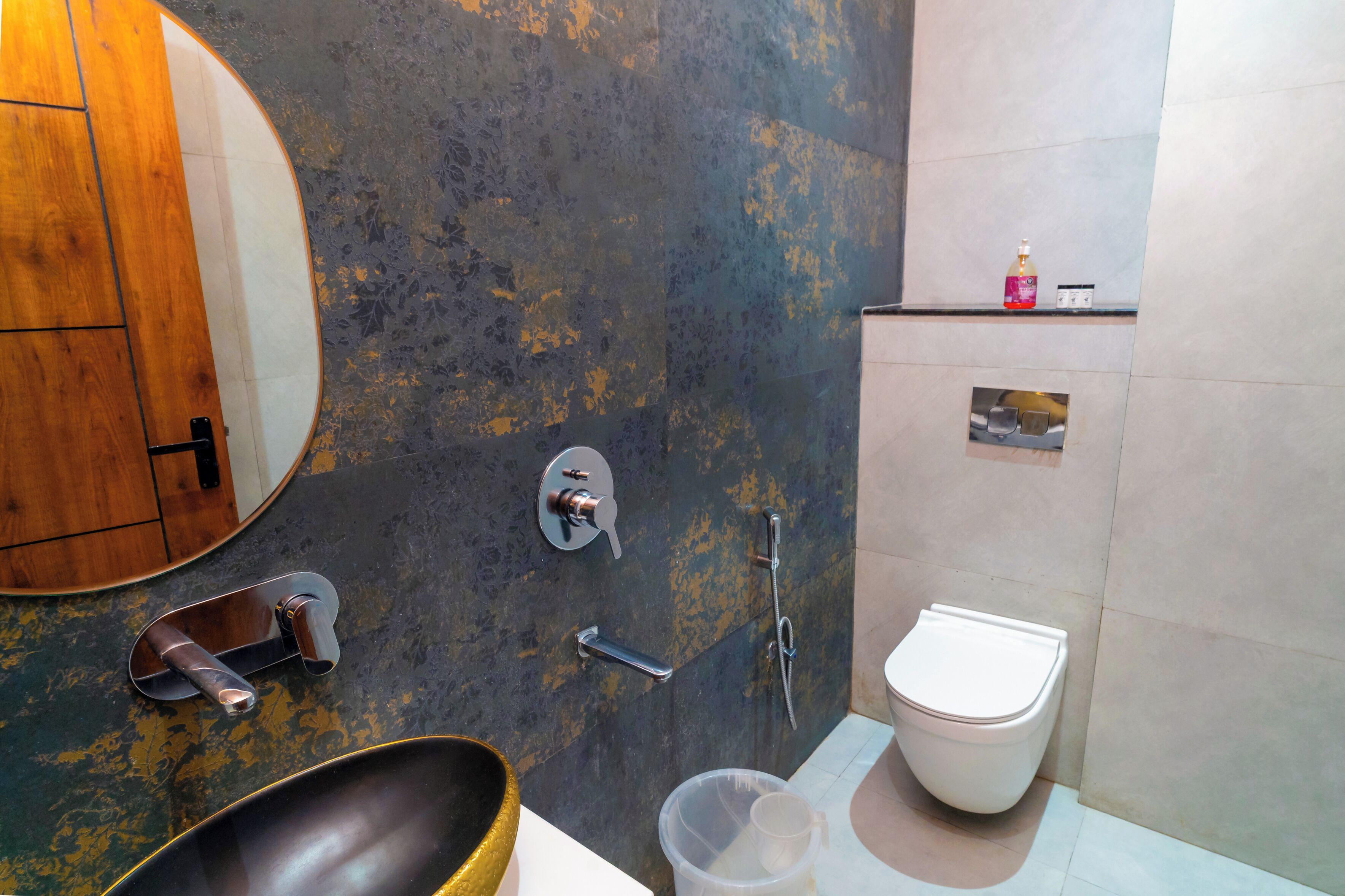 Ein Badezimmer mit einem Holzbadezimmer-Möbel, einem runden Spiegel, einem modernen Waschbecken, einer Toilette und einer Dusche mit Duschbrause.